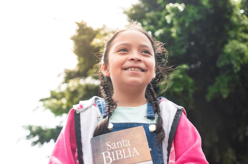 In Guatemala, 10-year-old Adriana is standing outside the Compassion centre holding a Bible.