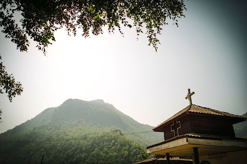 A church building with a mountain behind it.