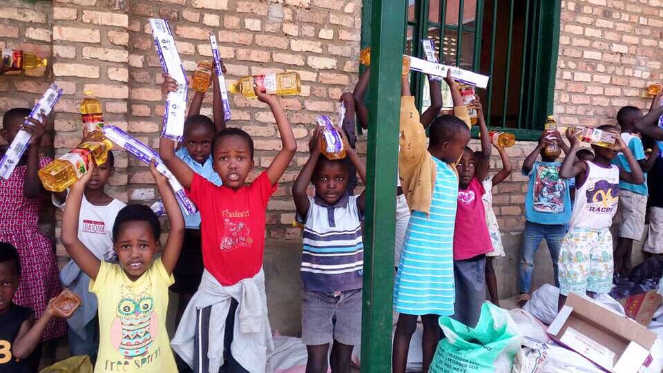 Kids stand on a porch and hold up different supplies that were given to them.